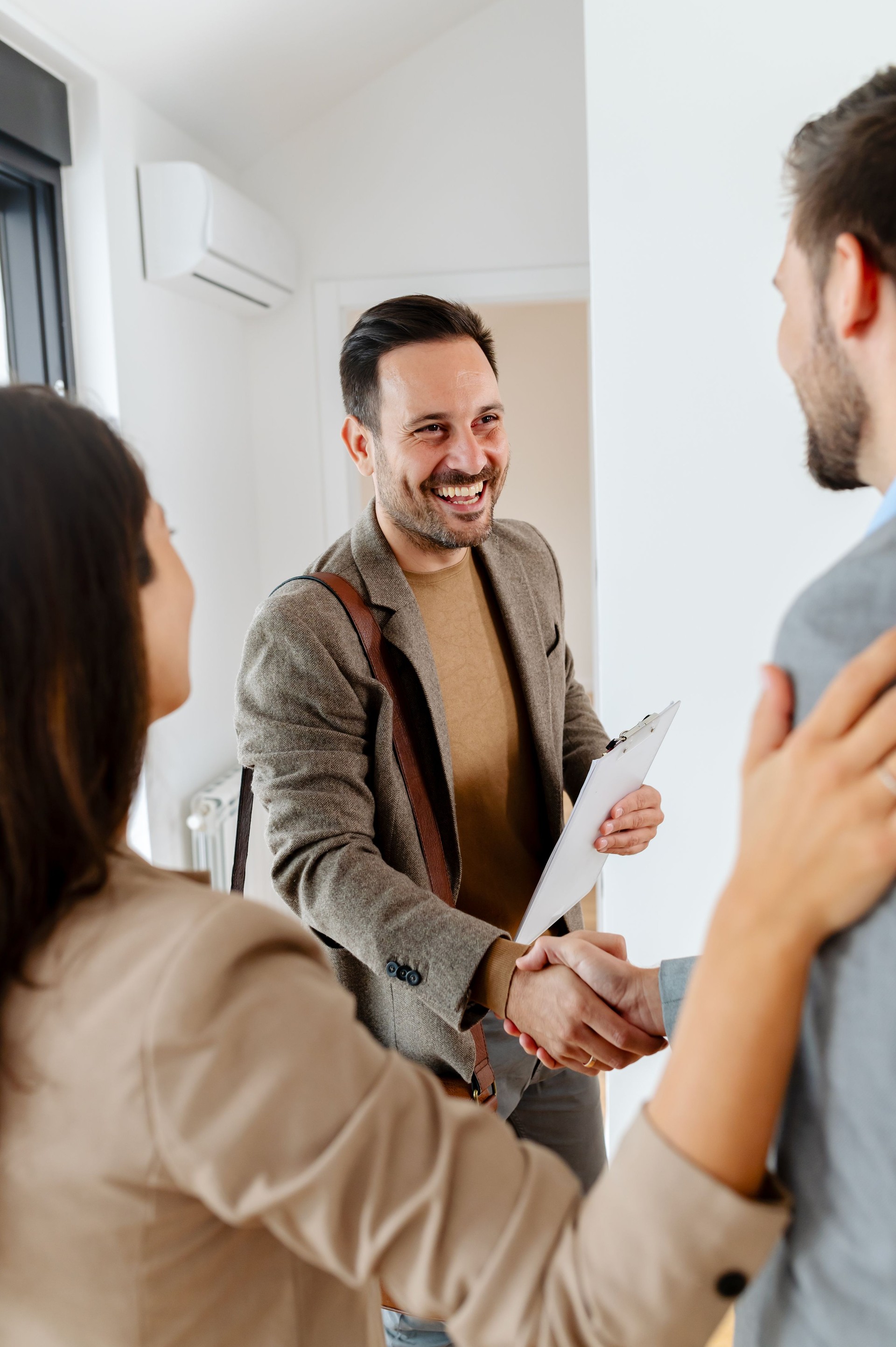 Cheerful couple expecting a baby, talking with a real-estate agent visiting an apartment for sale or for rent.